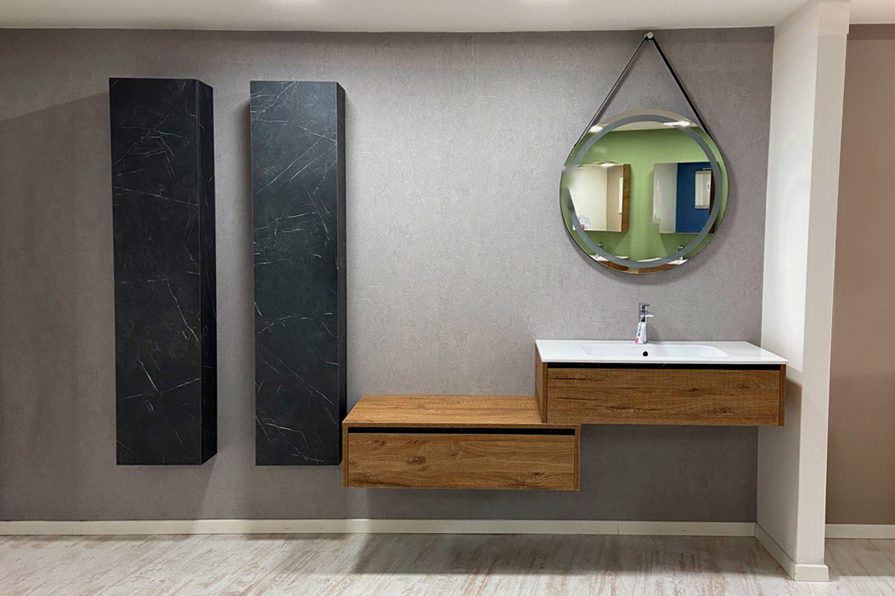 L'arredo bagno modello NAOMI è composto da due basi sospese (una porta lavabo e l'altra con cassetto), uno specchio tondo con illuminazione a led e due colonne sospese.